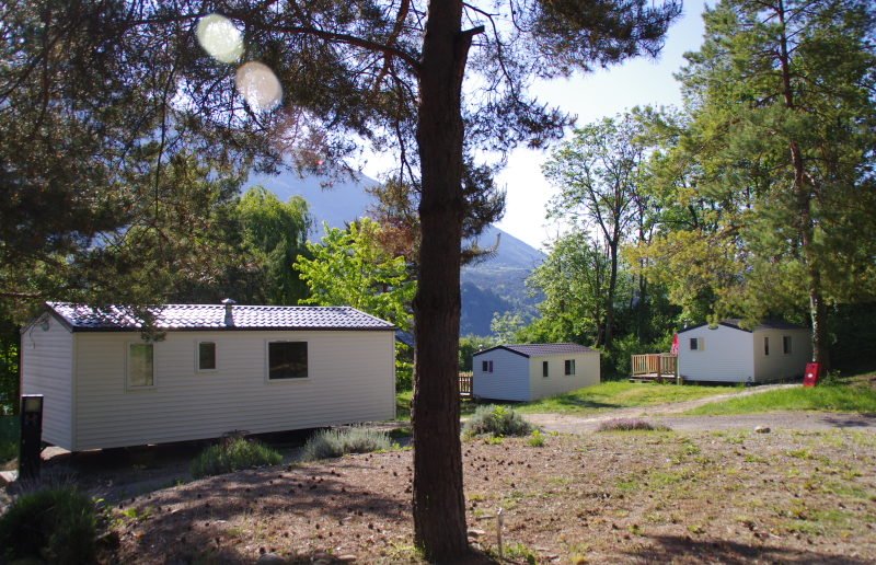 drie witte stacaravans op Camping De La Plage Treffort met in het midden op de voorgrond van de foto een boom