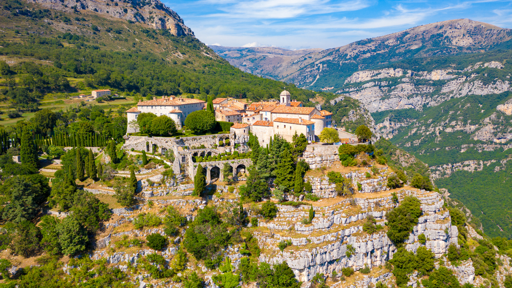 Huizen met oranje daken van het dorpje Gourdon gebouwd op een hoge rots en uitzicht op omliggende bergen in de Provence.