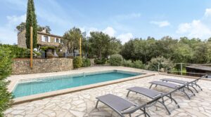 vier lege zonnebedjes aan een leeg zwembad bij een vakantiehuis in Plan de la Tour, Zuid-Frankrijk